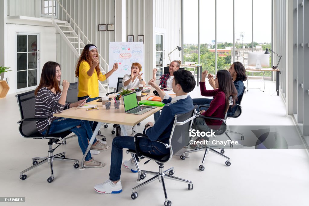 Group of young attractive asian creative design team meeting at office celebrating success or winner. Asian employee engaged together with effective and productive meeting and happy workplace concept. Agility Stock Photo