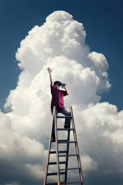 istock Young man on top of a ladder looking through binoculars. 1145145899