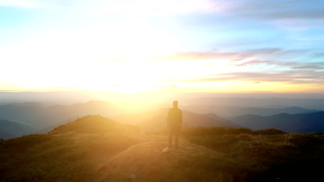The man standing on the top of the mountain with a beautiful sunrise