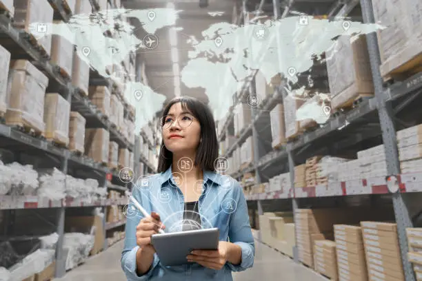 Photo of Portrait of happy young attractive asian entrepreneur woman looking at inventory in warehouse using smart tablet in management technology,  interconnected industry, asian small business sme concept.