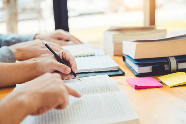 istock High school or college students studying and reading together in library 1145151209