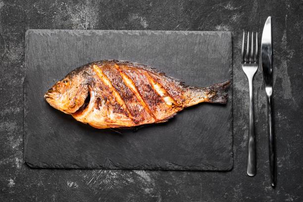 Grilled dorada only on a black stone tray top view.