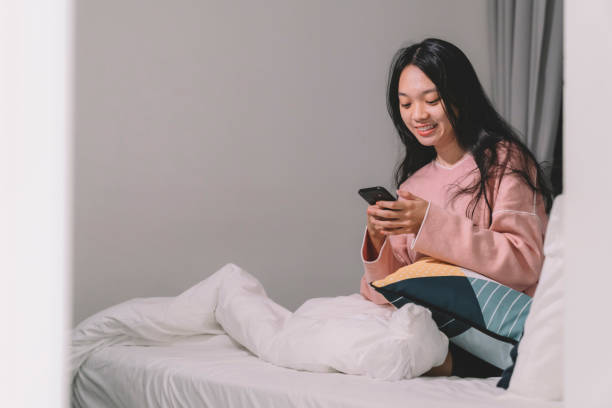 istock Asian chinese female at Home using phone alone smiling 1145155139