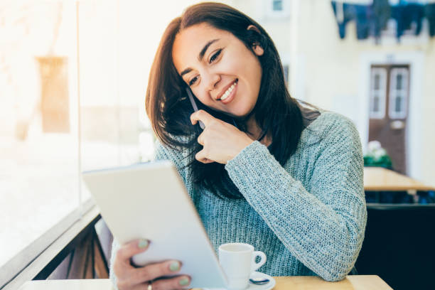 istock Smiling beautiful young woman using smartphone and tablet 1145170619