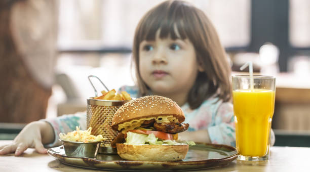 istock Little girl eats in a fast food cafe 1145173231