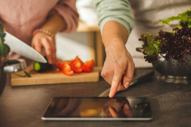 istock Pointing at recipe on digital tablet while preparing food 1145178557