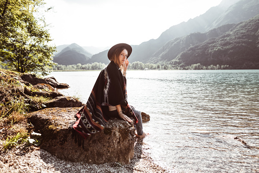 folk woman with a poncho sitting on a stone
