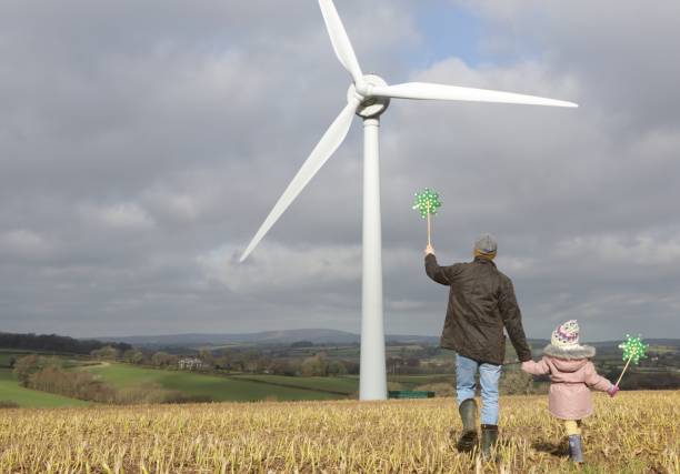 Father and daughter walk to wind turbine