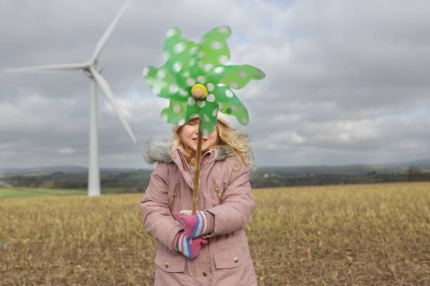 ragazza si trova di fronte alla turbina eolica - green environmental conservation meadow wind foto e immagini stock