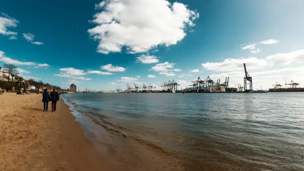 Beach scene at the Elbe with container harbor in Hamburg, Germany.