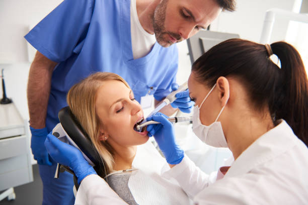 young woman is getting treatment in dentist's office - dentist office dentists chair dental equipment white imagens e fotografias de stock