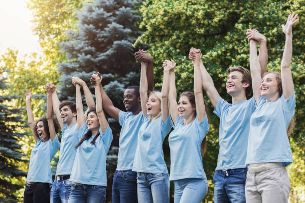 istock Group of young volunteers join hands in park 1145183148