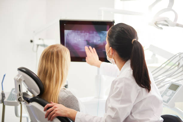 rückansicht von zahnarzt und patient mit blick auf röntgenbild - dentist dentist office patient discussion stock-fotos und bilder