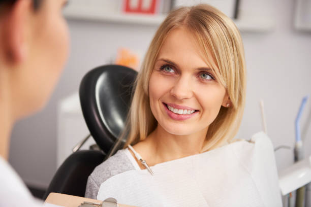 радующаяся и улыбчивая женщина в клинике стоматолога - smiling dentist office dentists chair women стоковые фото и изображения