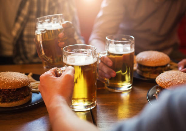 men drinking beer and eating burgers - beer hamburger american culture beef imagens e fotografias de stock