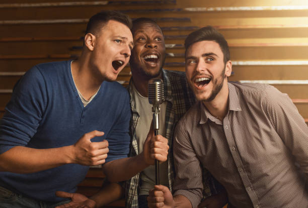 Happy friends singing karaoke together in bar Happy male friends singing karaoke together in bar three amigos stock pictures, royalty-free photos & images