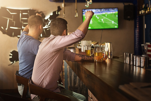 Dos amigos viendo partido de fútbol y bebiendo cerveza photo