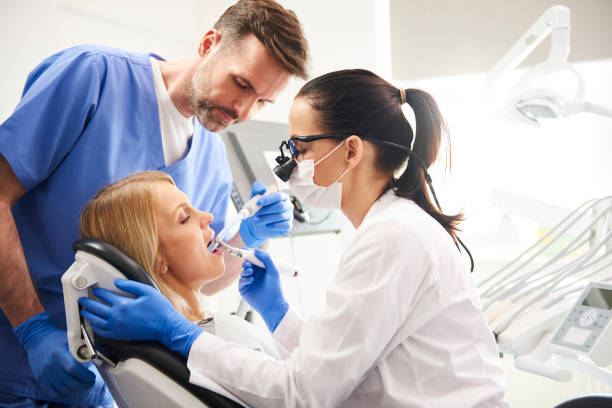 Dentist and her assistant doing their work in dentist's clinic stock photo