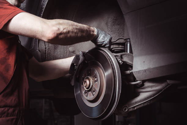 un mécanicien dans le centre de service vérifie la suspension de la voiture. effectue un remplacement saisonnier des roues. - automotive repair center photos et images de collection