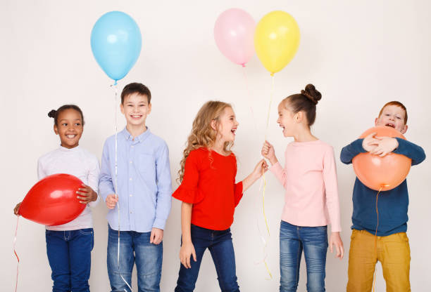 istock Children with colourful balloons over light wall 1145190092