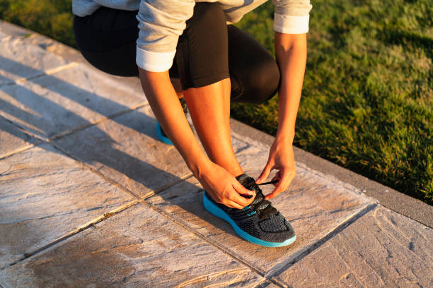 Young woman tying shoelace of sneakers to make outwork training running. Fitness and healthy lifestyle Young woman tying shoelace of sneakers to make outwork training running. Fitness and healthy lifestyle lace up stock pictures, royalty-free photos & images