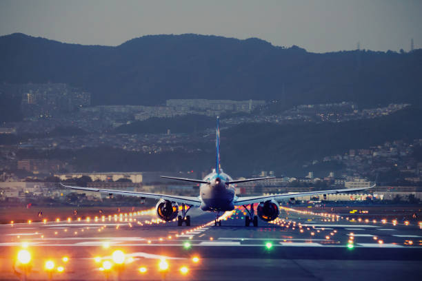 avión aterrizando durante la hora azul - aterrizar fotografías e imágenes de stock