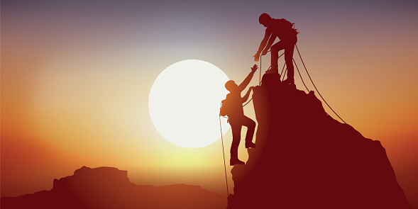 Concept of solidarity, with two mountaineers reaching out to each other when they reach the top of a mountain, after successfully climbing it
