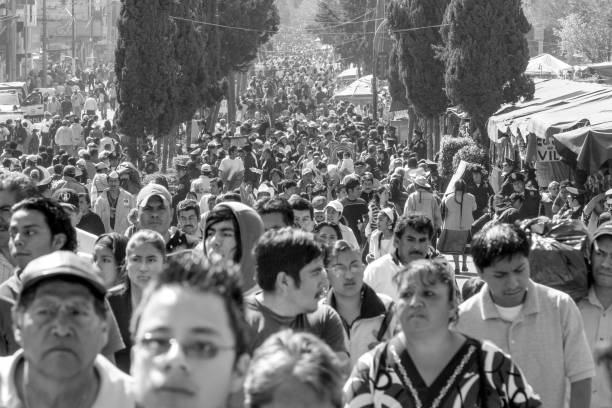 Thousands of faithful and pilgrims along the avenue of the Basilica de Santa María de Guadalupe in Mexico City Mexico City, Mexico, Dic 12 - Veneration in honor of the Virgin of Guadalupe in Mexico City is among the most widespread and loved in the Catholic world. Every year around December 12th, millions of people visit the sanctuary of Our Lady of Guadalupe in the Cerro del Tepeyac where, as tradition tells, the Virgin Mary appeared in 1531. In the photo: An immense and long corridor of people approaches the Sanctuary along the Calzada de Guadalupe church black and white people praying stock pictures, royalty-free photos & images