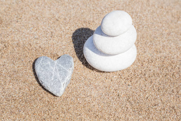 istock heart shaped stone and stack of pebbles on balance on sand 1145196091