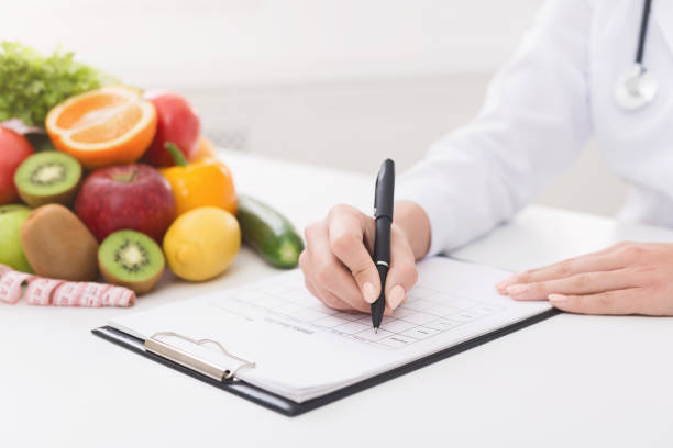 istock Female nutritionist doctor writing vegetable diet plan 1145199203