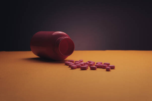 istock Beautiful pink bottle and pink pills on a orange background. 1145201558
