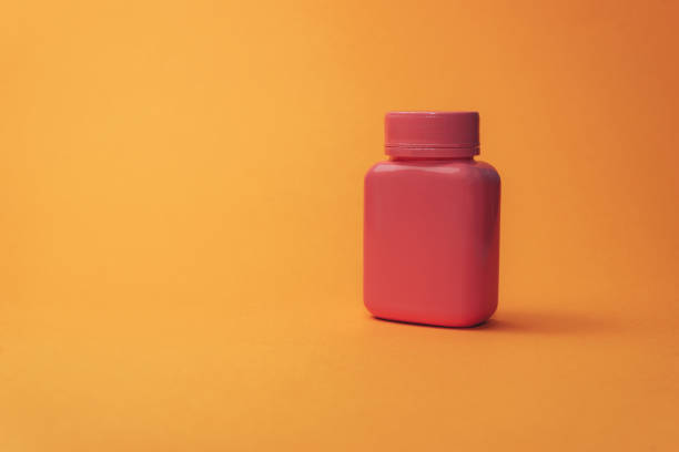 istock Pink bottle for pills on a orange background. 1145201612