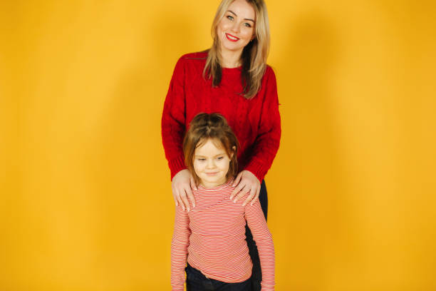 istock Mom and daughter standing on the yellow background in studio 1145201712