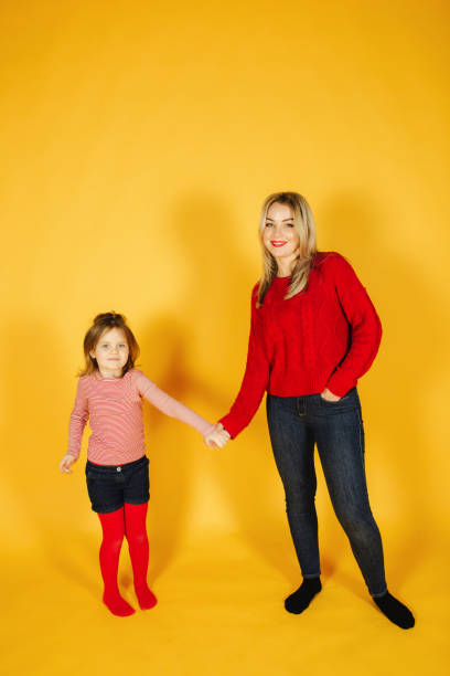istock Mom and daughter standing on the yellow background in studio 1145201722