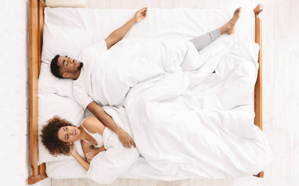 mujer triste acostada en la cama con el hombre dormido - stretching boyfriend indoors lifestyles fotografías e imágenes de stock