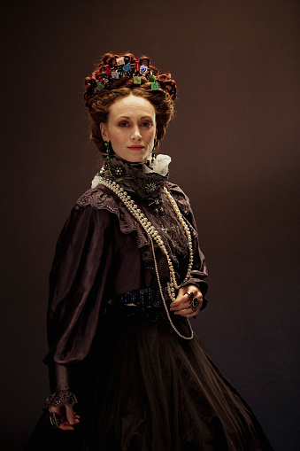 Queen Elizabeth I concept. The woman portraying her is dressed traditionally but with little images of app icons scattered in her hair. She is looking into the camera standing confidently.