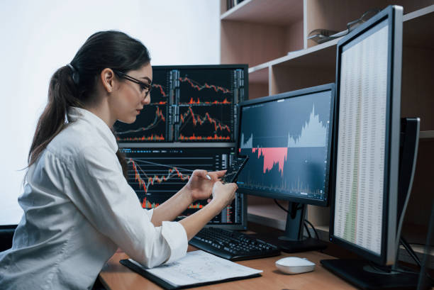 istock Gorgeous brunette. Woman working online in the office with multiple computer screens in index charts 1145204487
