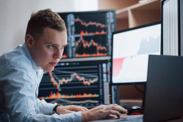 istock Thinks what to do next. Man working online in the office with multiple computer screens in index charts 1145204728