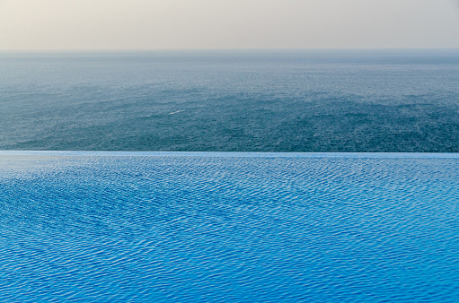 Infinity pool with crystal blue water view to sea  ocean.
