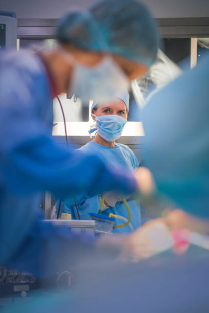 enfermera femenina que mira al cirujano que opera paciente - surgery emergency room hospital operating room fotografías e imágenes de stock