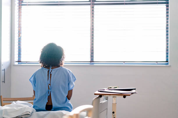 istock Lonely female patient looking through window 1145212449