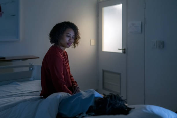 Woman looking at ill boy sleeping on bed in ward Young mother looking at ill son sleeping on hospital bed. Boy is relaxing while woman sitting in ward. They are at children's hospital. night hospital bed stock pictures, royalty-free photos & images