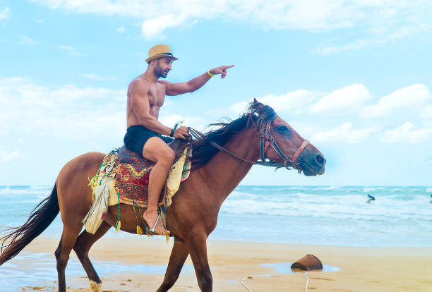 istock Shirtless man riding a horse on the beach 1145213457