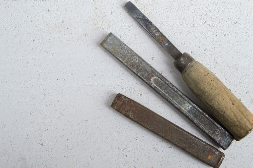 Three old chisels on a concrete floor close up.