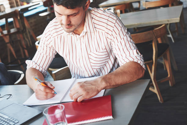 istock Making some corrections. Adult man sits in cafe at daytime and making reports in notepad with laptop on the table 1145222134