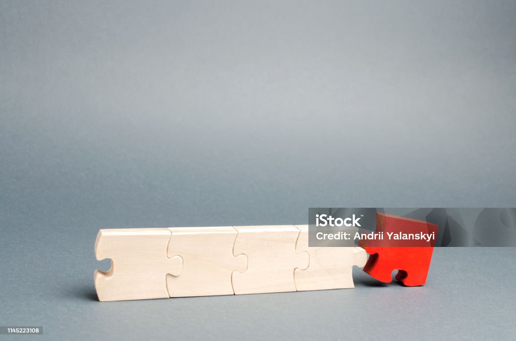 The red puzzle is disconnected from the rest. The concept of individuality and uniqueness. Individual opinion. Betrayal in the team. Sabotage of workers. The dismissal of an employee. Staff reduction. Being Fired Stock Photo
