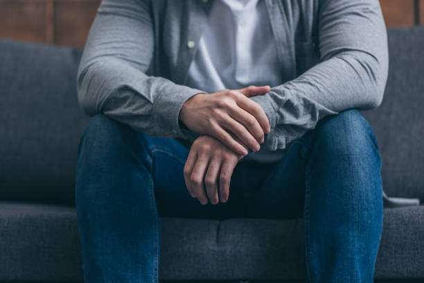 istock cropped view of man sitting on sofa at home 1145223265