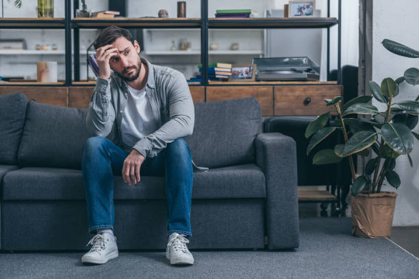 istock depressed man sitting on couch, touching face and grieving at home 1145223275