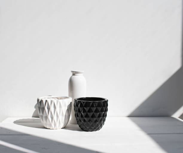 istock Vase, black-and-white pots on wood table. White wall, background with sunlight and shadows. Modern interior. 1145223944