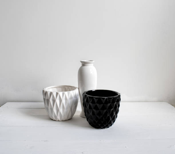 istock Vase, black-and-white pots on wood table. White wall, background with sunlight and shadows. Modern interior. 1145223945